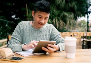 person sitting at a picnic table looking at tablet