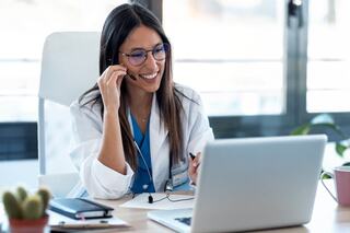 medical doctor sitting at desk pointing to a document using a pen held in their right hand